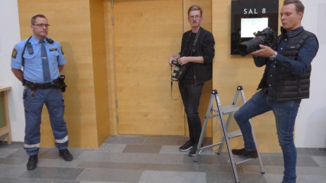 Fotografer hade bland annat riggat upp med en pall för att fotografera den häktade industriledaren. Men de fick tji. Industrimannen fördes in i salen genom sidodörren utan handfängsel sedan dörren för allmänheten stängts.