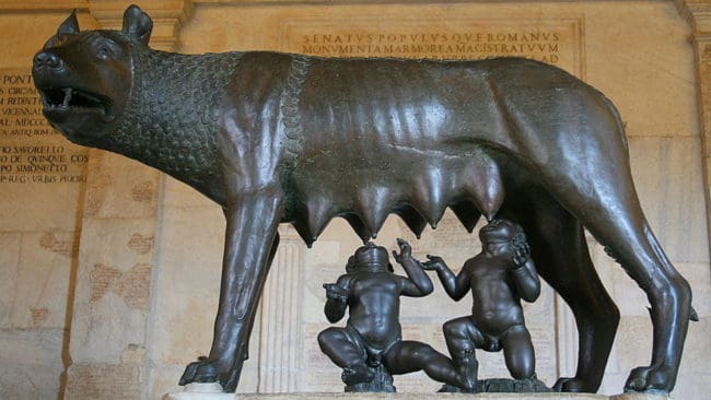 Enligt romersk mytologi var det Romulus och hans tvillingbror Remus som grundade Rom den 21 april 753 f.Kr. Som nyfödda sattes de ut för att dö men blev räddade av en varginna som gav dem di. Skulpturen finns på Museo Nuovo i Palazzo dei Conservatori i Rom.
